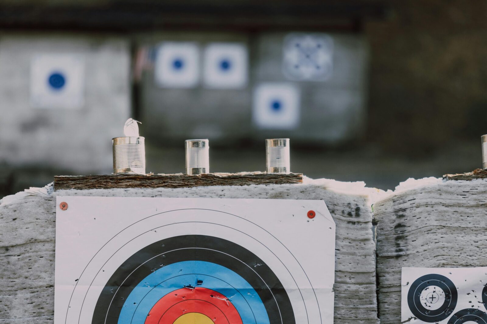 Close-up of archery targets and steel cans used for target practice at an outdoor range.