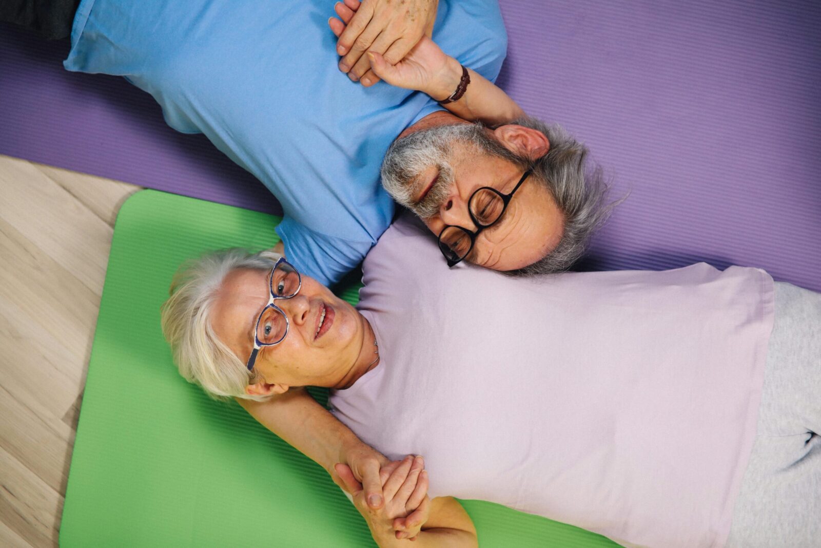 Senior couple lying on yoga mats, enjoying togetherness and positive aging.